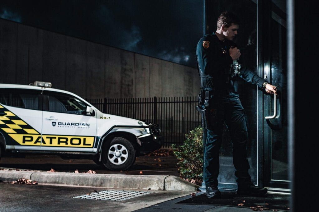 A patrol officer checking a glass entry door at night