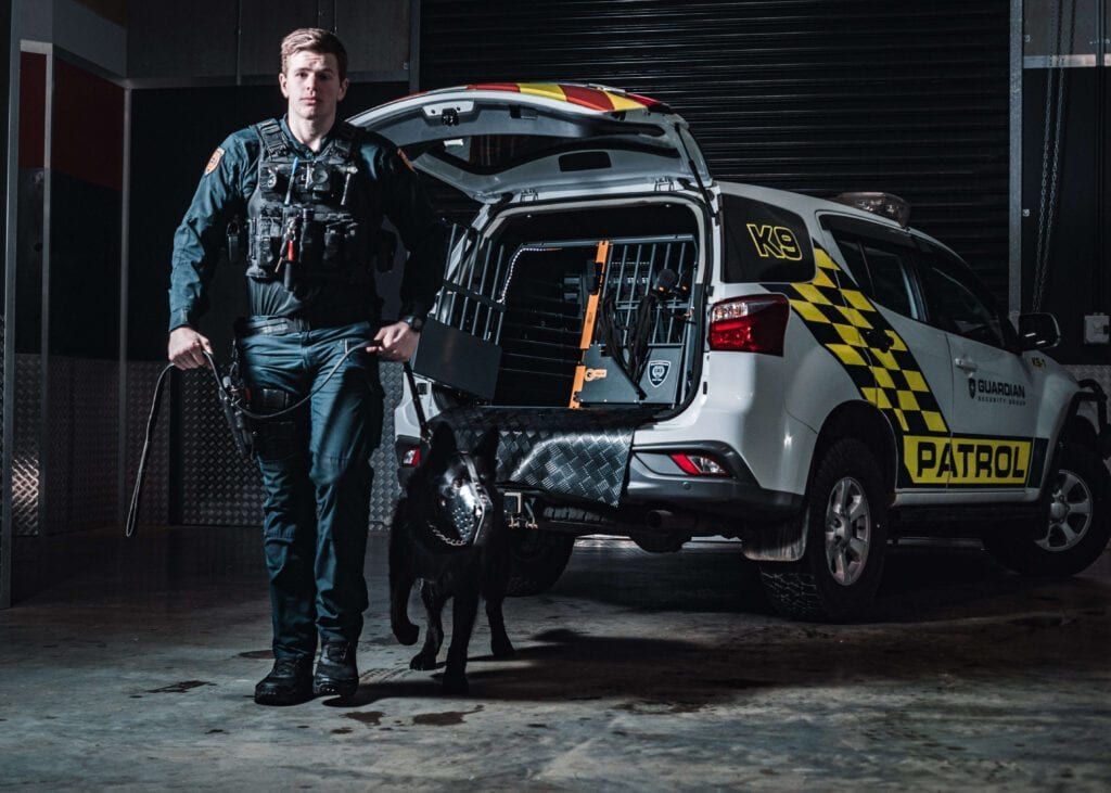 A patrol officer and dog beside a marked patrol vehicle